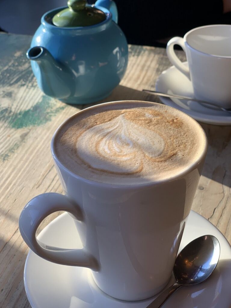 Latte with heart-shaped foam art and teapot — symbolizing warmth, comfort, and clarity after counseling for women in Orange County