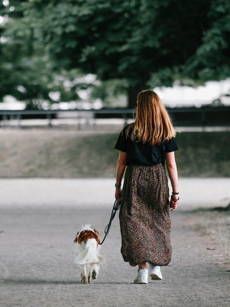 Woman walking her dog under tall trees — representing clarity, calm, and emotional grounding after counseling for women in Orange County including Newport Beach and Orange.
