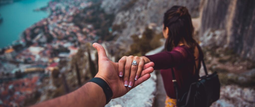 Man holding a woman’s hand as she walks ahead, symbolizing emotional distance and uncertainty in a relationship