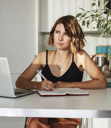 Woman writing on a notebook, represents how you can improve your executive function skills and feel more in control with ADHD therapy for adults.