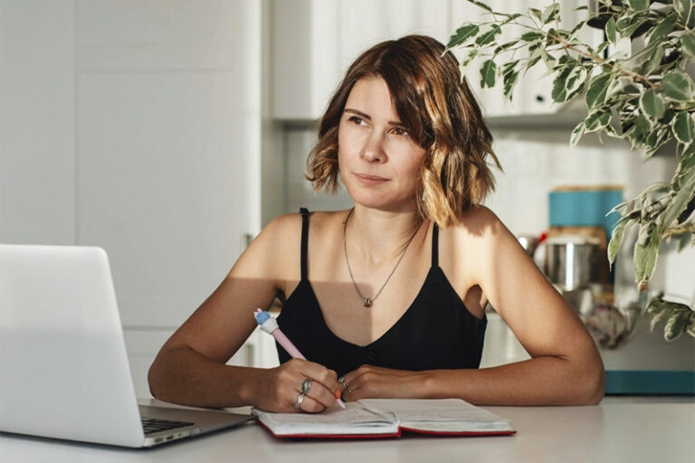 Woman writing on a notebook, represents how you can improve your executive function skills and feel more in control with ADHD therapy for adults in Orange County.