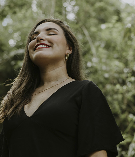 Happy woman in a black dress surrounded by nature, represents how a grief counselor can help provide the support you need during loss.