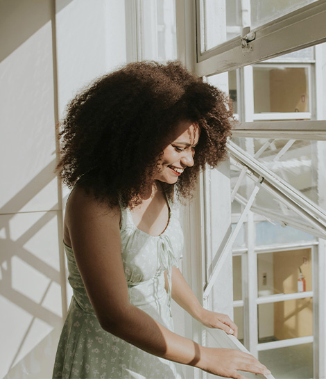 Woman enjoying the sunlight by her window, represents how working with a depression therapist in Newport Beach and across Orange County can help you heal.
