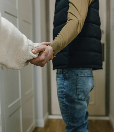Couple letting go of each other hand as one partner leaves their house, represents how divorce counseling can help you move forward.