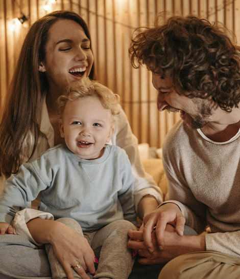 Parents smiling with their small child, represents how you can overcome your challenges together by working with a parenting counselor.