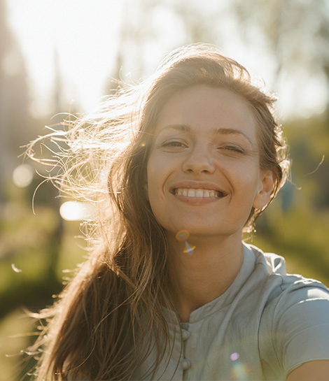 Woman smiling in the sunlight, represents how you can feel more connected to yourself and your faith.