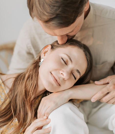 Man kissing his partner on the forehead, represents how working with a Gottman method trained therapist can help couples strengthen their relationship.