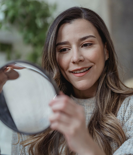 Woman looking at her reflection in the mirror, represents how ifs therapy can help you see every part of you and start healing.