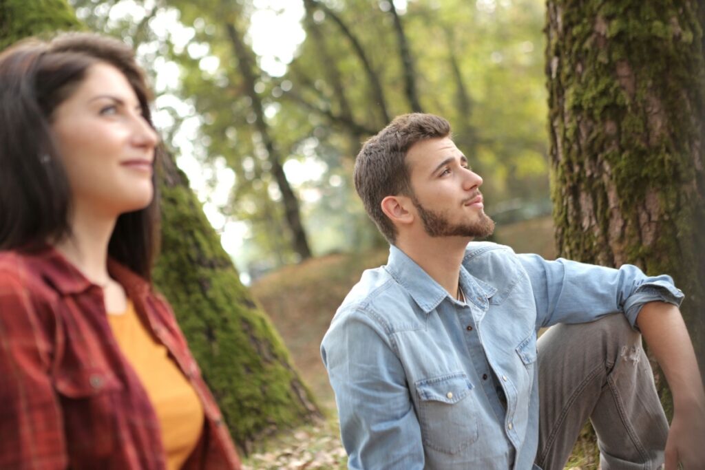 Couple sitting outdoors, each looking off in a different direction, reflecting quiet uncertainty about commitment