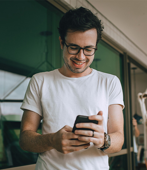 Man smiling while texting on his phone, represents how learning DBT skills like STOP can help you navigate difficult moments in your daily life.