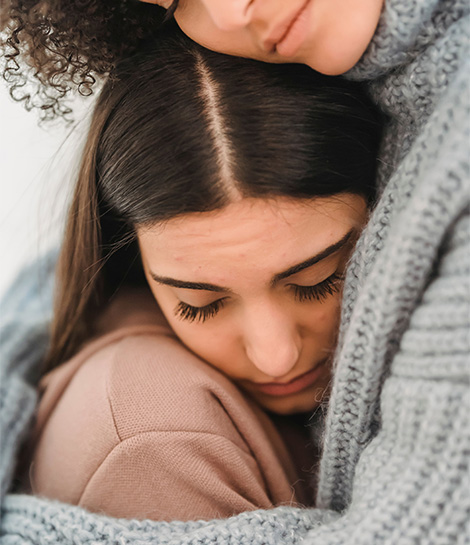 Woman being hugged by her friend, represents how learning DBT skills through therapy can help you improve your relationships.